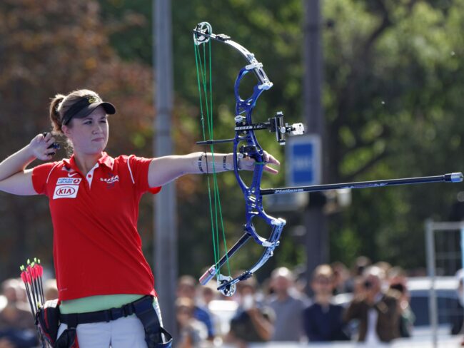 Professional compound bow shooter releases her arrow toward a target