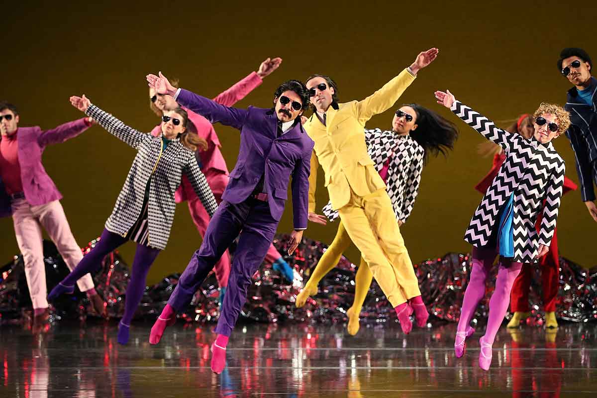 Dancers standing on their toes in 80's style clothing and sunglasses at Missouri performing arts center