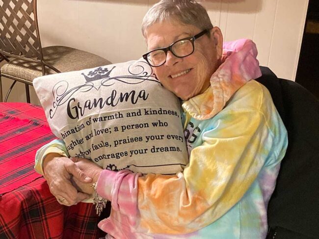 Woman hugging pillow that says Grandma
