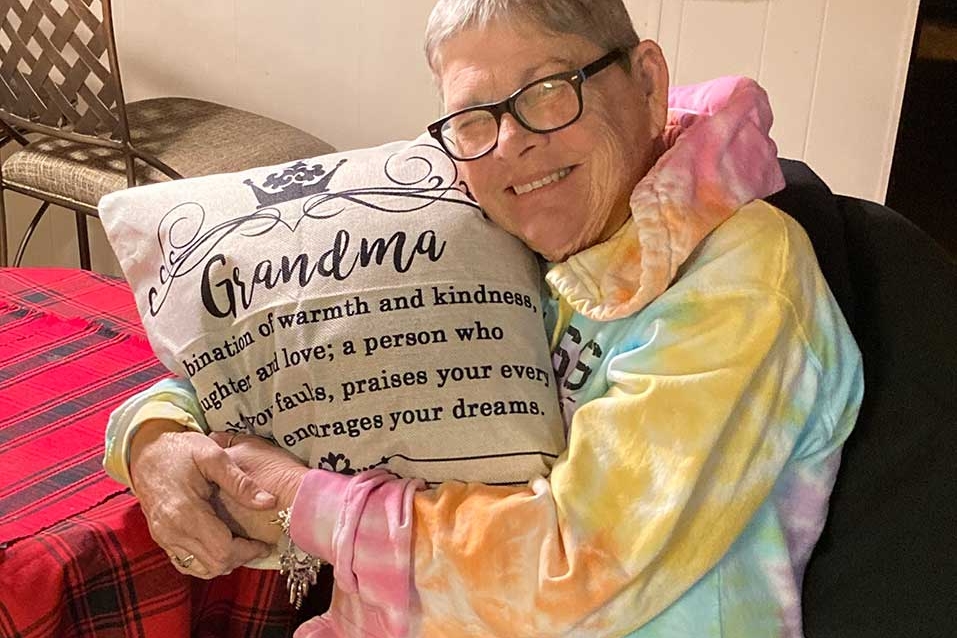 Woman hugging pillow that says Grandma