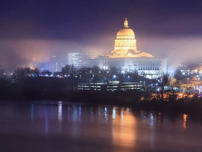 Missouri Capitol building at night with reflection off the Missouri River.