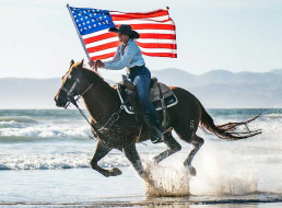 Woman riding horse and carrying flag on the beach