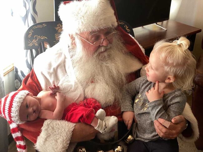 Stephen Johnson aka Santa Claus with two small children on his lap.